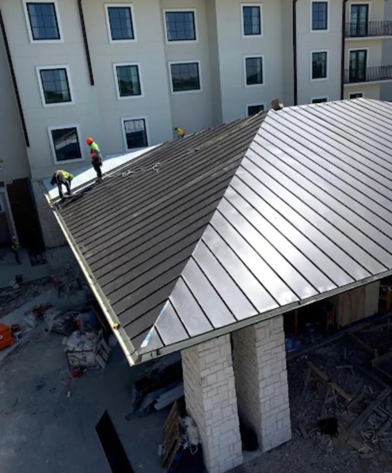 Crew installing standing seam metal roof panels on a commercial project in Fairfax